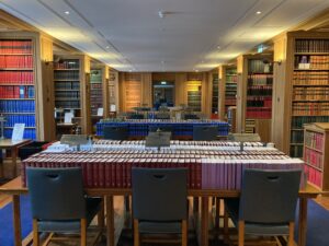 Library room of oak book cases and tables in the middle of the room covered in books