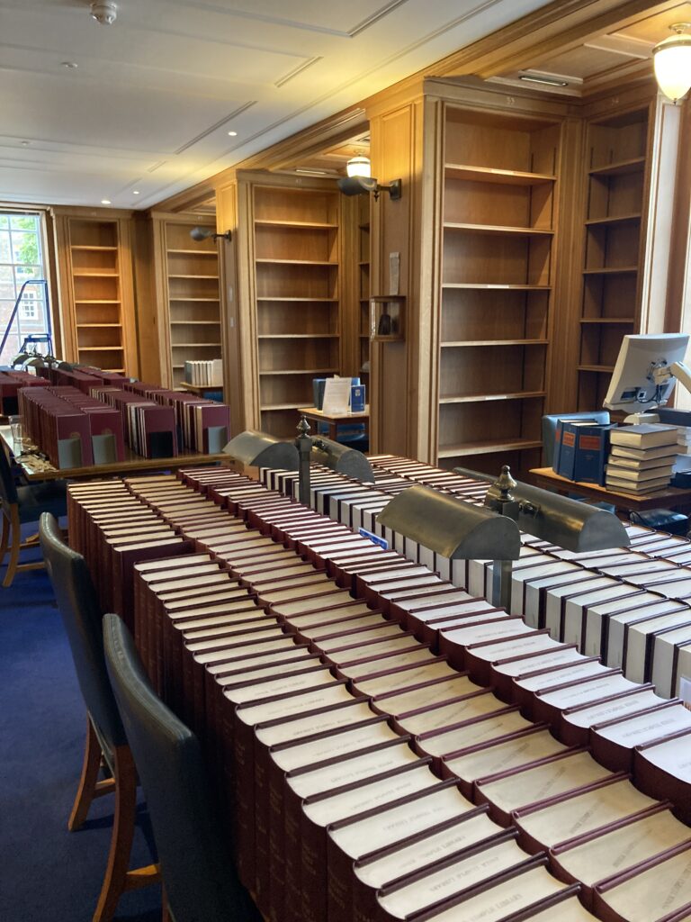 Library room of oak panelled bookshelves that are empty with books on the tables in the middle of the room