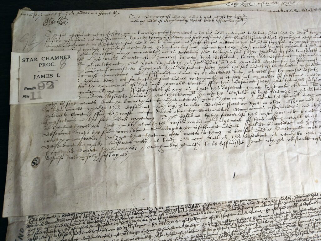 Old pieces of paper with handwriting on them and a label stitched to them with the text Star Chamber Proc. James I