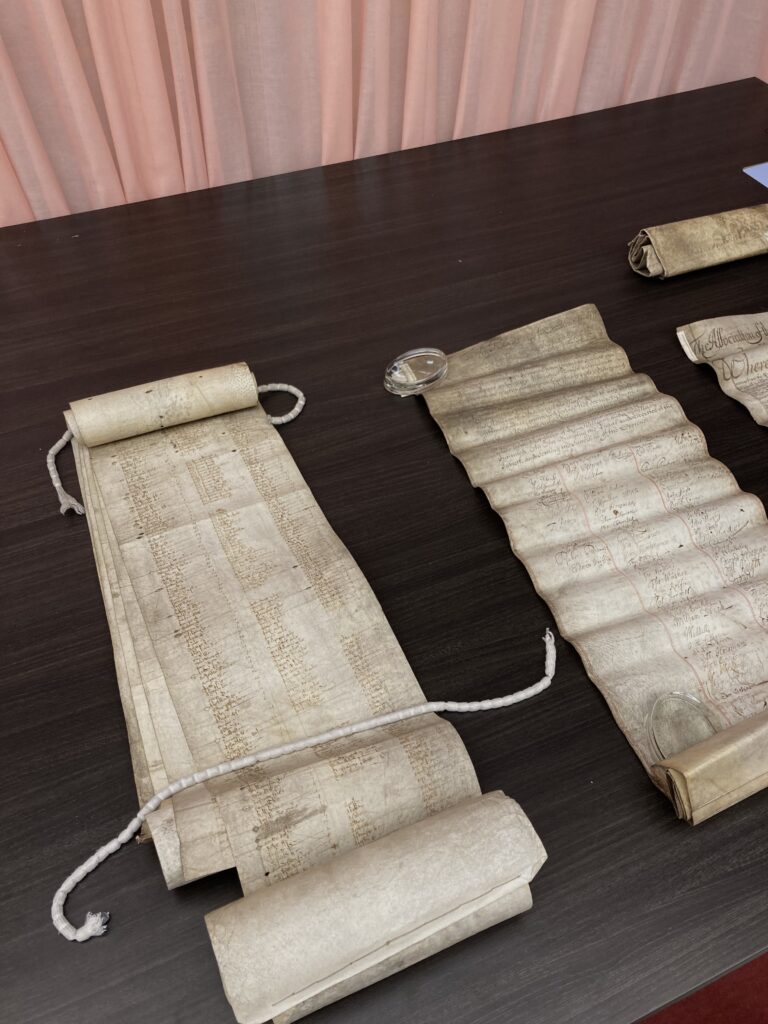 Roles of old paper, unrolled, with lists of names