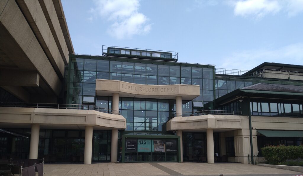 View of a glass and concrete building with Public Record Office inscribed in the concrete above the doorway