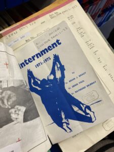 Front cover of Internment magazine 1971-1975 with a blue drawing of blue drawing of a person facing a wall, arms upstretched, legs back