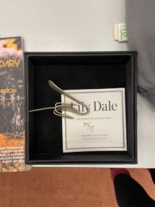 A black box containing a bent metal fork and a piece of paper with text: Lily Dale, Authentic Flatware 30/77 Presented with Seance by Shannon Taggart