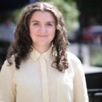 Photo of woman with long curly dark hair and light yellow blouse.
